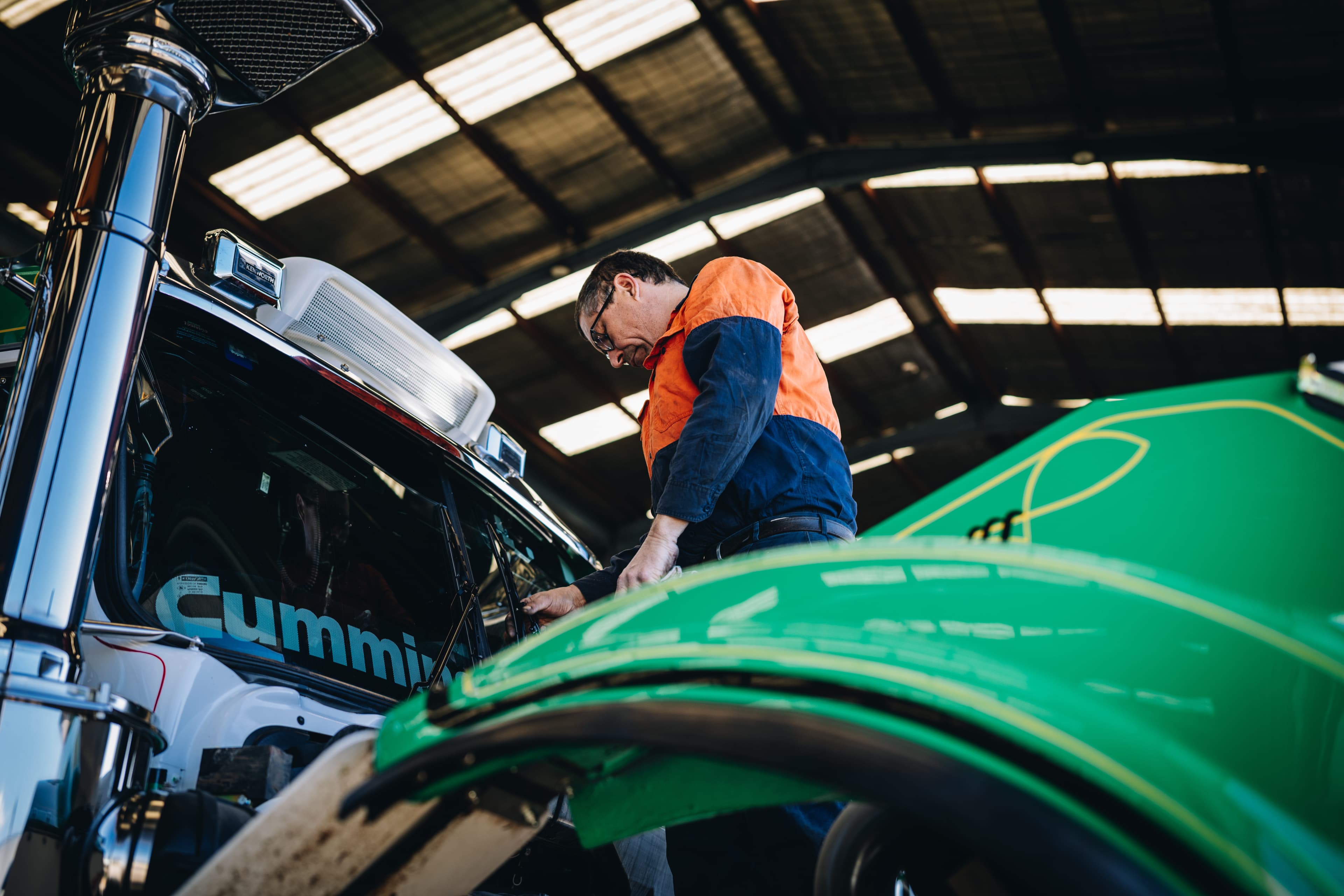 Mechanic working under the raised bonnet of a Kenworth