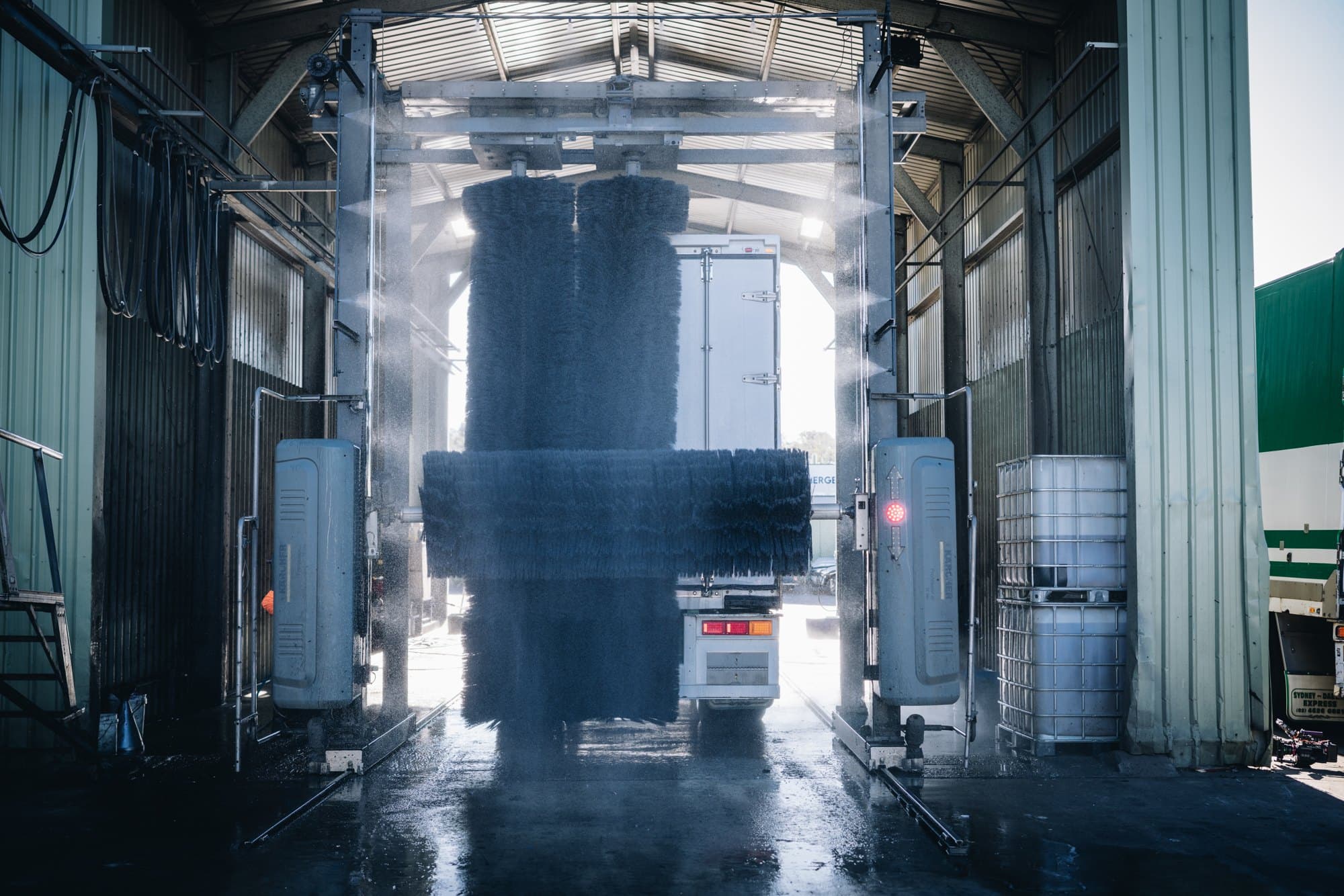 A refrigerated trailer going through the wash bay, seen from behind