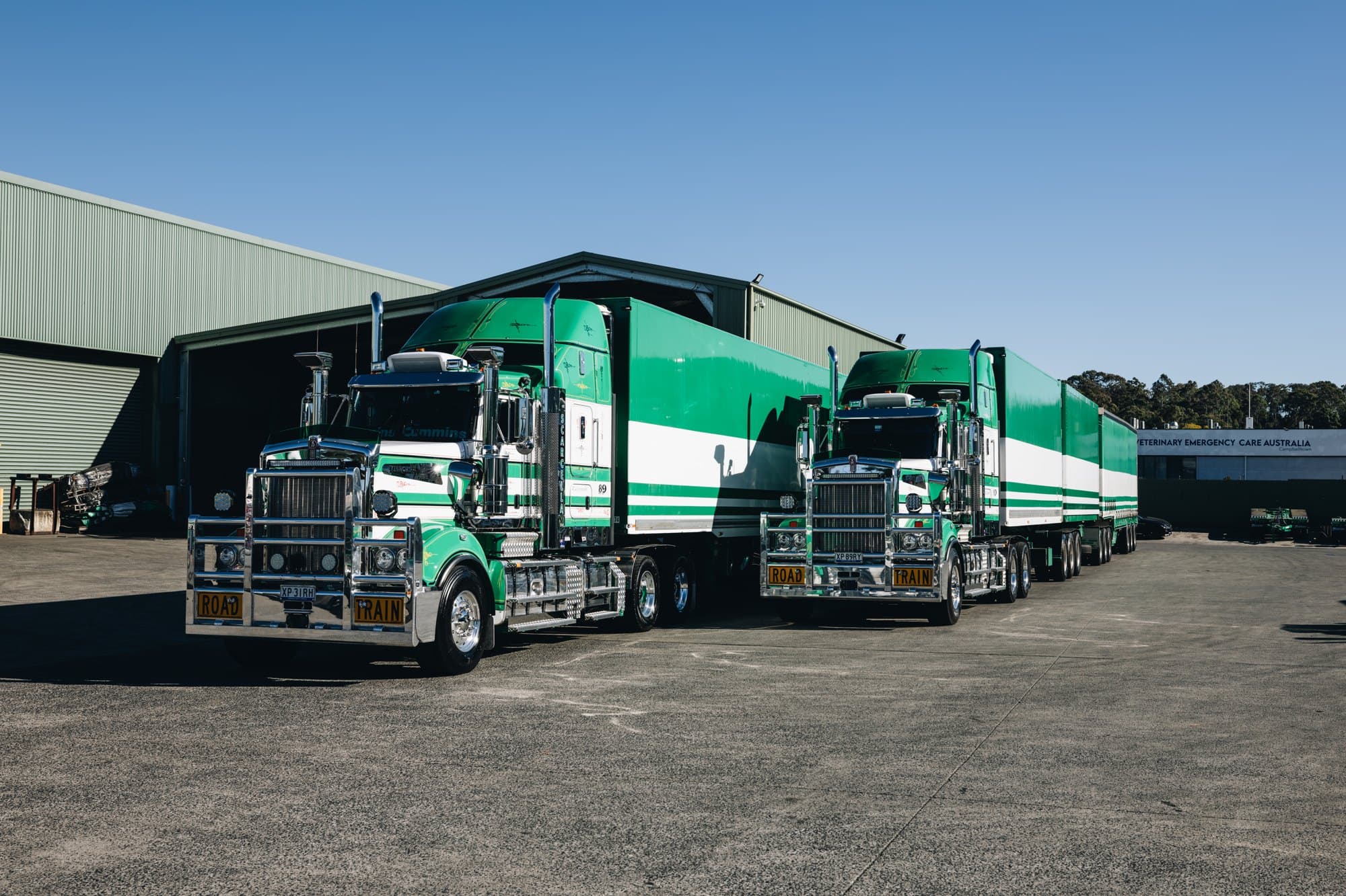Two Kenworth 909s side by side beside the wash bay at the Campbelltown depot